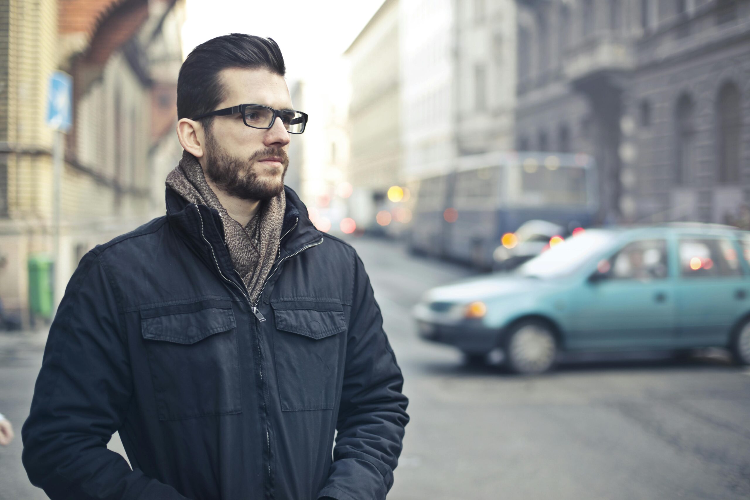 Fashionable man with glasses standing on a bustling street in Budapest, Hungary.